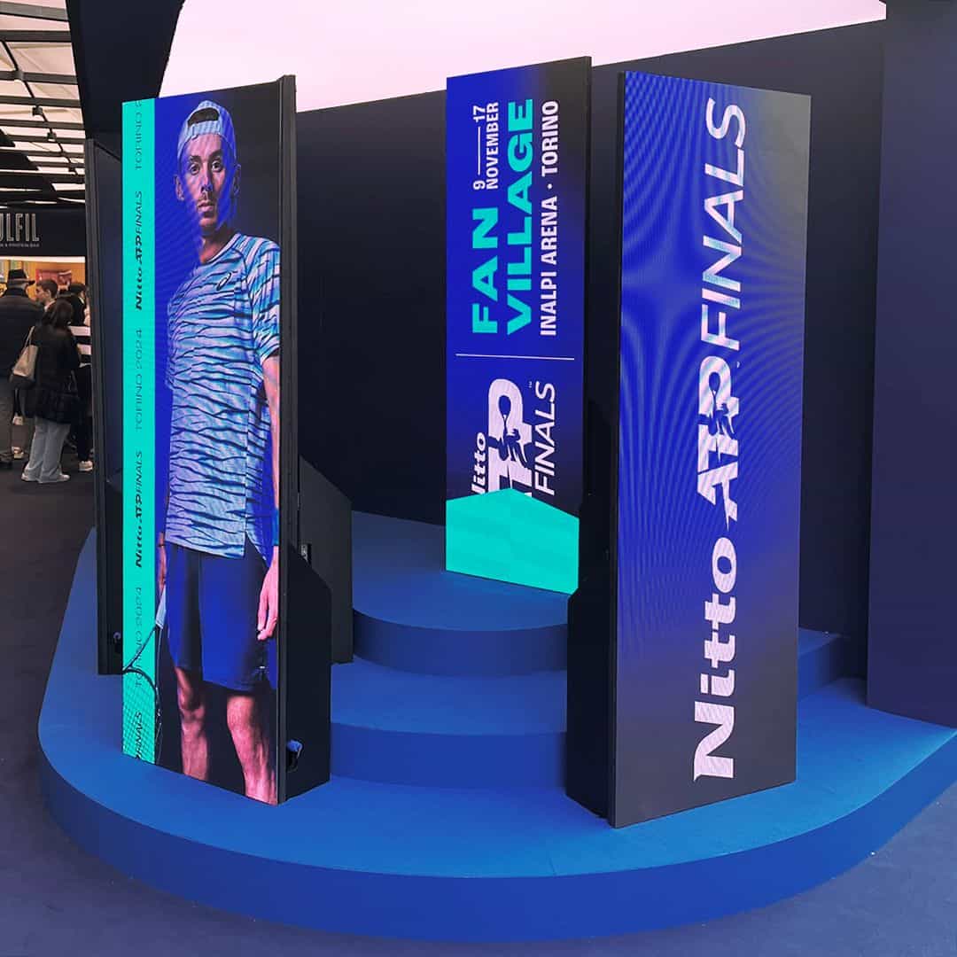 Un'immagine di display digitali e banner pubblicitari allestiti per il torneo di tennis ATP Finals a Torino, con loghi e dettagli dell'evento.