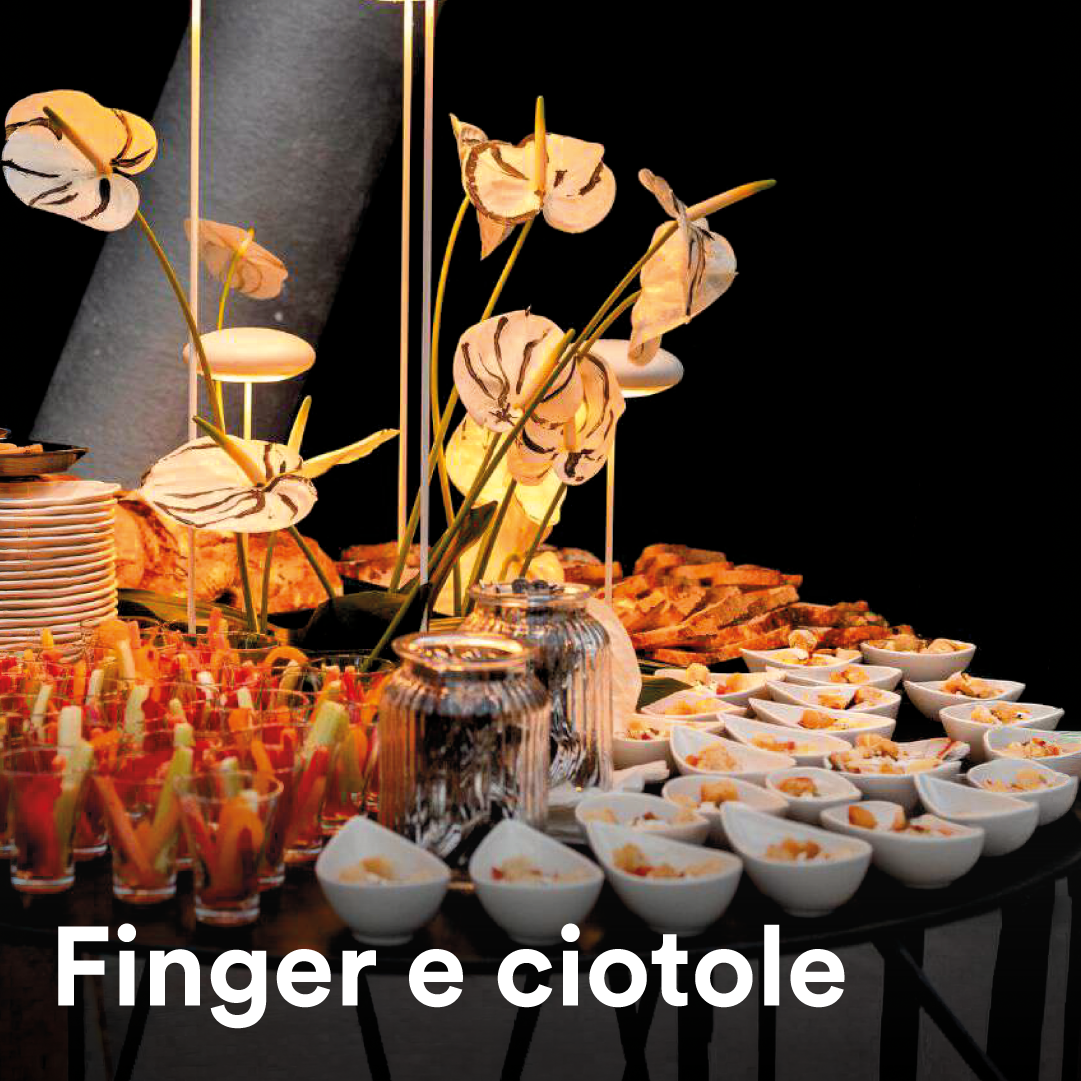 Buffet di finger food e ciotole di antipasti, decorato con fiori di carta, ideale per eventi e catering.