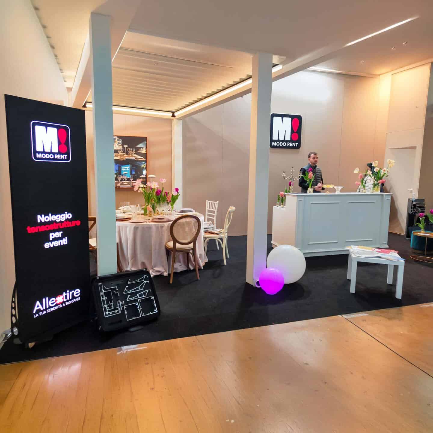 Sedie e tavoli eleganti allestiti per un evento aziendale o privato, con decorazioni floreali e illuminazione moderna, all’interno di uno spazio affittato da Modorent per occasioni speciali.