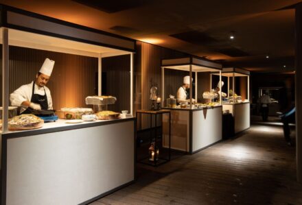 Servizio di catering con chef che prepara piatti gourmet in un ambiente elegante e moderno.