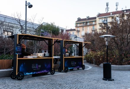 Due carretti Bancarella Gourmet risplendono in un ambiente urbano all'aperto, circondati da edifici e alberi.