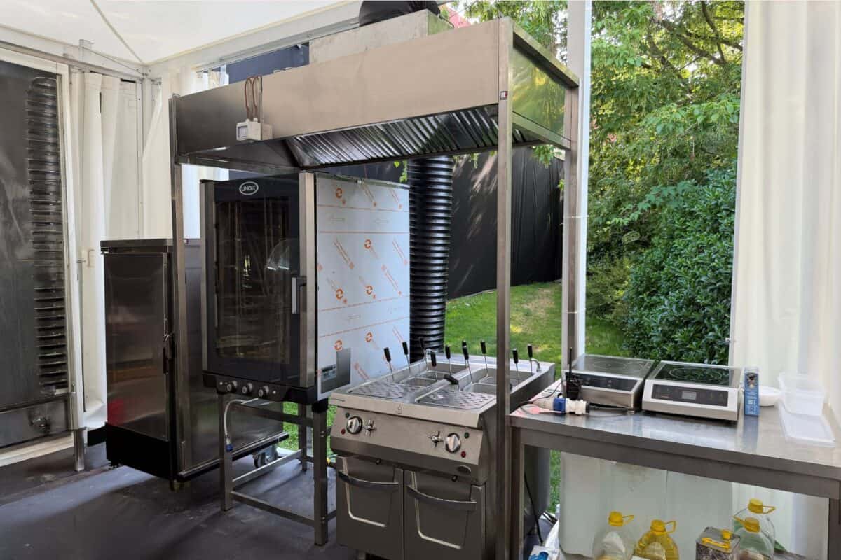 Forno a legna professionale con sistema di ventilazione e area di preparazione, ideale per eventi e ristorazione all'aperto.