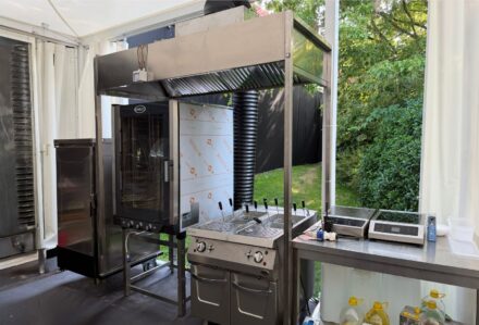 Forno a legna professionale con sistema di ventilazione e area di preparazione, ideale per eventi e ristorazione all'aperto.