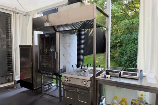 Forno a legna professionale con sistema di ventilazione e area di preparazione, ideale per eventi e ristorazione all'aperto.