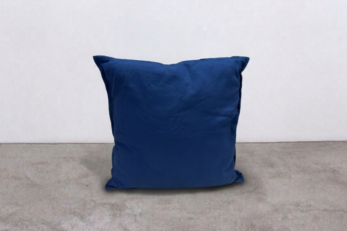 Cuscino blu in tessuto morbido su pavimento in moquette grigia, ideale per decorare e rendere confortevole ogni spazio living o zona relax. Perfetto per ambienti moderni e accoglienti.