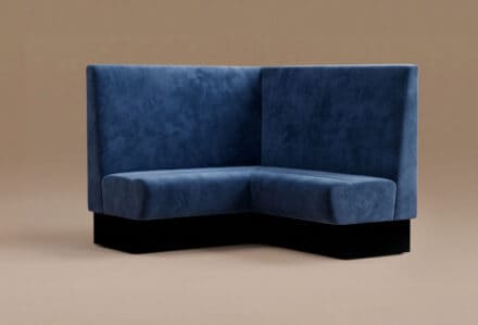 Divano angolare in velluto blu scuro con schienale alto, ideale per arredare soggiorni eleganti e moderni.