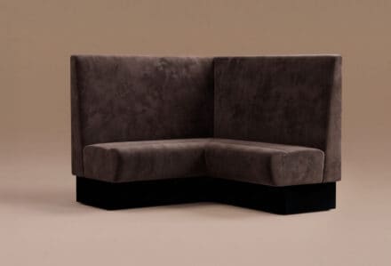 Divano angolare moderno in tessuto scuro con base nera, ideale per arredare salotti eleganti e contemporanei.