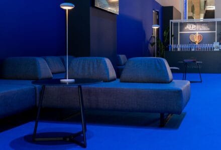 Elegante area lounge con divani blu e illuminazione moderna, ideale per eventi e incontri professionali presso Modorent.