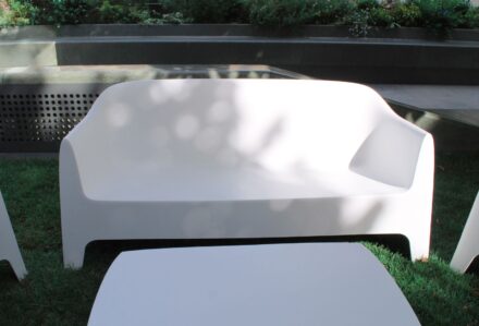 Divano bianco moderno in giardino con sedie abbinate, ambiente esterno elegante e luminoso.