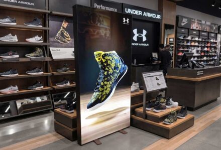 Espositore luminoso bifacciale modello Lumilight Easy Assembly di Modorent in un negozio di articoli sportivi, ideale per pubblicità instore di grande impatto.
