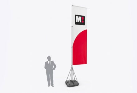 Bandiera pubblicitaria rettangolare su piantana metallica con base zavorrata. Il telo della bandiera è bianco nella parte superiore, con un logo quadrato nero contenente la lettera 'M' bianca e un punto esclamativo rosso, e presenta una forma circolare rossa nella parte inferiore. Sulla sinistra, la sagoma grigia di un uomo in abito fornisce un riferimento visivo per l'altezza. Sfondo bianco