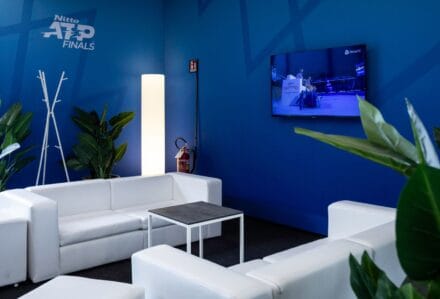 Lampada da terra Fluo moderna e luminosa in un ambiente di attesa con divani bianchi e piante verdi, ideale per creare un'atmosfera accogliente e contemporanea.