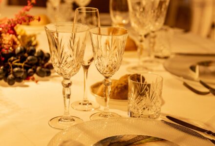 Set di bicchieri da vino e acqua in cristallo su tavolo elegante con decorazioni floreali e posate di alta qualità.