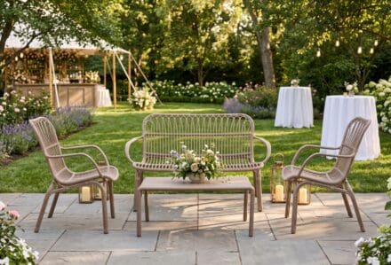 Set di sedie e tavolini in giardino con decorazioni floreali e luci soffuse, ideale per eventi all'aperto.