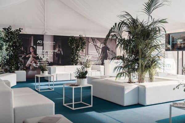 Panca Sirio Bianca in ambiente elegante e moderno, decorata con piante verdi e arredi bianchi, ideale per eventi e incontri all'aperto sotto una grande tensostruttura.