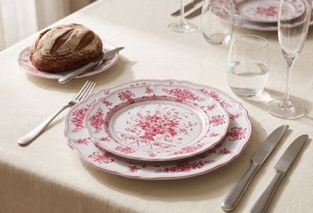 Piatti in porcellana con motivo floreale rosso su tavola elegante per cena.