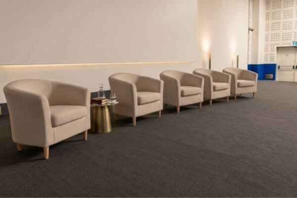 Poltrona Ios in tessuto beige con braccioli morbidi, ideale per ambienti di attesa o sale riunioni, con design elegante e confortevole, perfetta per arredare con stile.