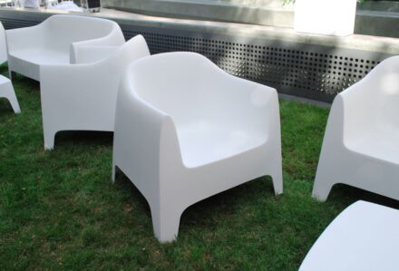 Sedie moderne bianche in plastica su prato verde, ambiente esterno con luce naturale, design minimalista e confortevole.