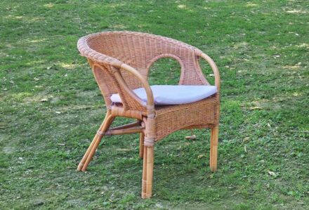 Sedia in vimini con cuscino bianco su prato verde, ideale per arredamento esterno e giardini.