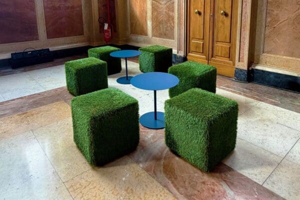 Set di pouf eco in erba artificiale con tavolini blu in un ambiente elegante.