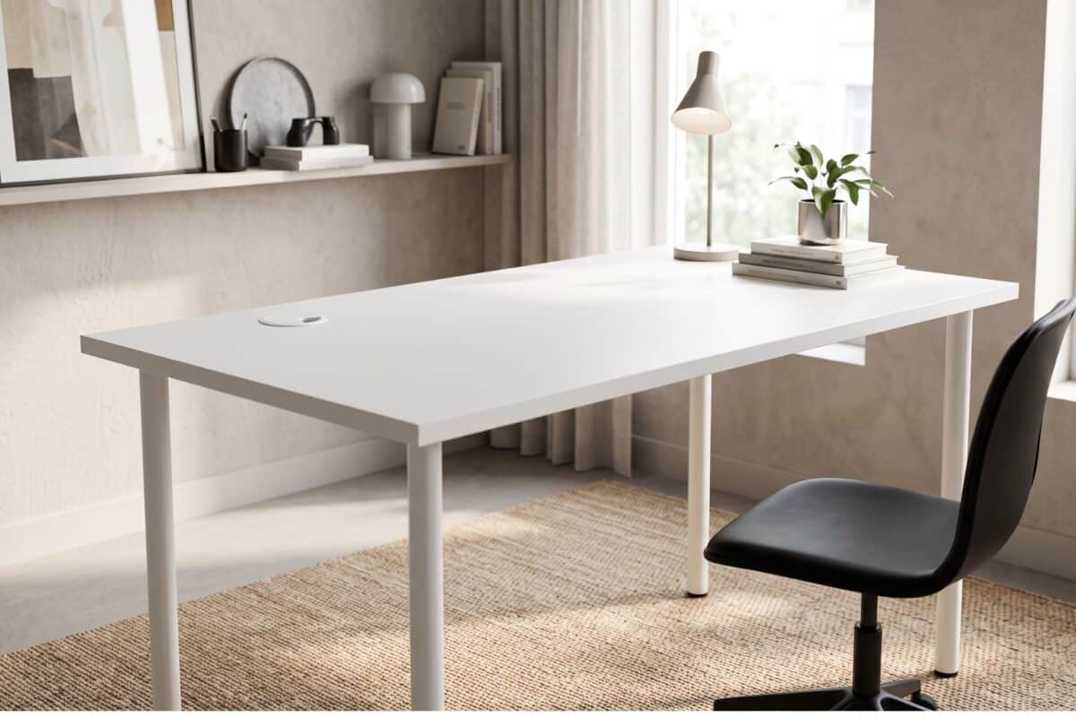 Scrivania moderna bianca in un ufficio luminoso con piante e decorazioni minimaliste.