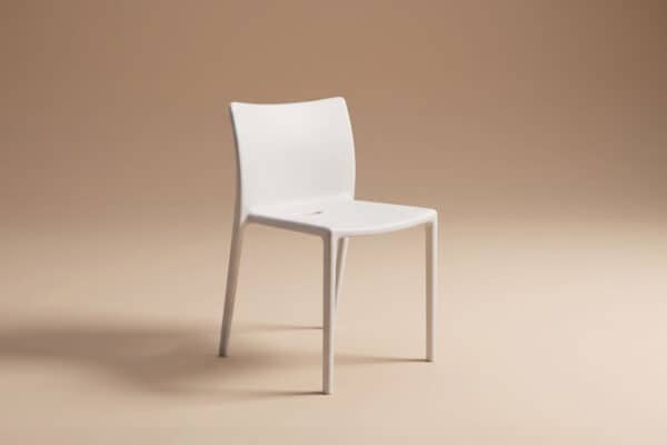 Sedia moderna bianca con schienale curvo e gambe sottili su sfondo beige neutro.
