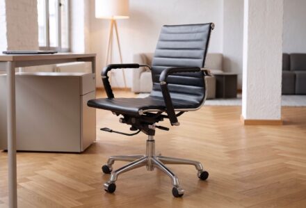 Sedia da ufficio ergonomica nera con braccioli in un ambiente moderno e luminoso.