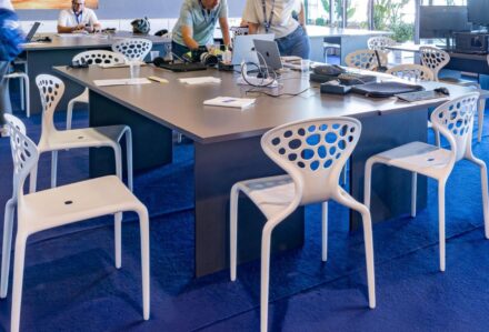 Sedia Supernatural Bianca in un ambiente moderno con tavolo da riunione e persone al lavoro.