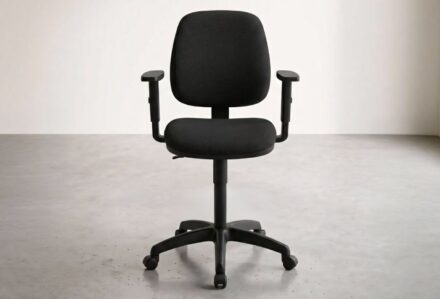 Sedia da ufficio nera con braccioli regolabili in un ambiente minimalista luminoso.