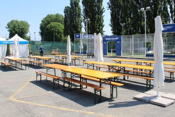 Arredi per esterni con tavoli e panche in legno, ideale per eventi all'aperto presso Set Birreria Classic, con area relax e spazi per socializzare in un ambiente estivo e accogliente.