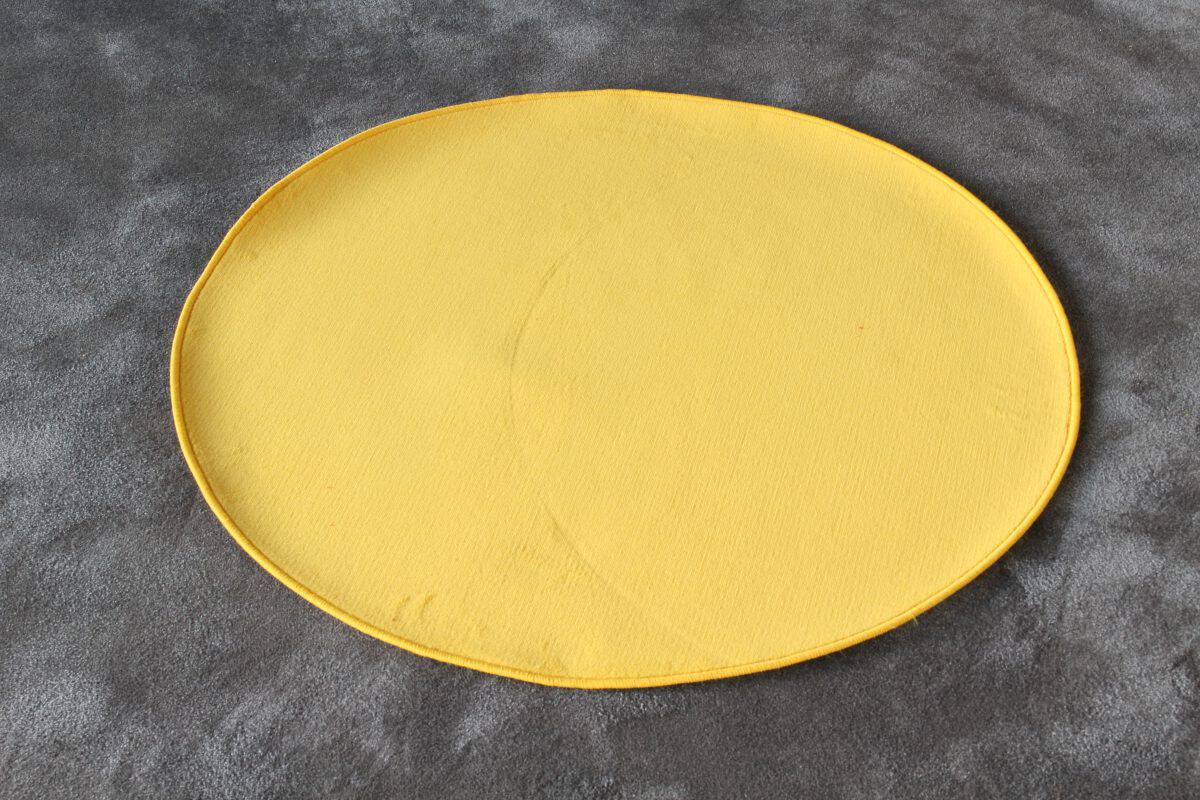 Un "Tappeto rotondo diam. 100 cm" di colore rosso è appoggiato su una superficie grigia testurizzata.