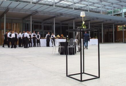 Gruppo di persone in abiti formali che partecipano a un evento all'aperto con tavoli e decorazioni eleganti.