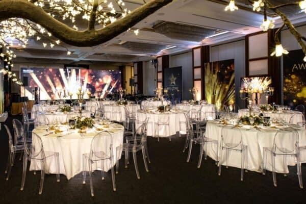 Sala elegante per eventi con decorazioni luminose, tavoli imbanditi e atmosfera raffinata, ideale per matrimoni e cerimonie di classe.