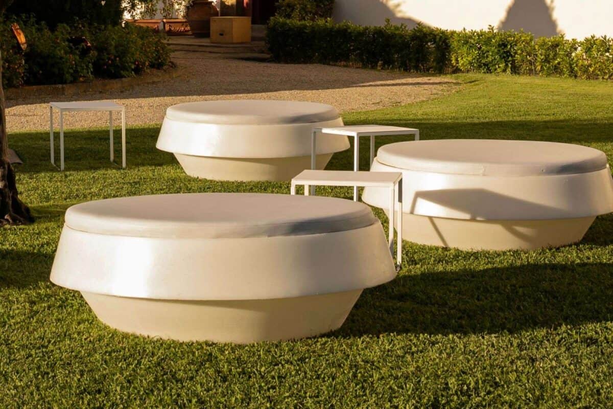 Design innovativo di sedute moderne in cemento bianco su prato verde, ideale per spazi esterni eleganti e contemporanei.