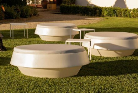 Design innovativo di sedute moderne in cemento bianco su prato verde, ideale per spazi esterni eleganti e contemporanei.